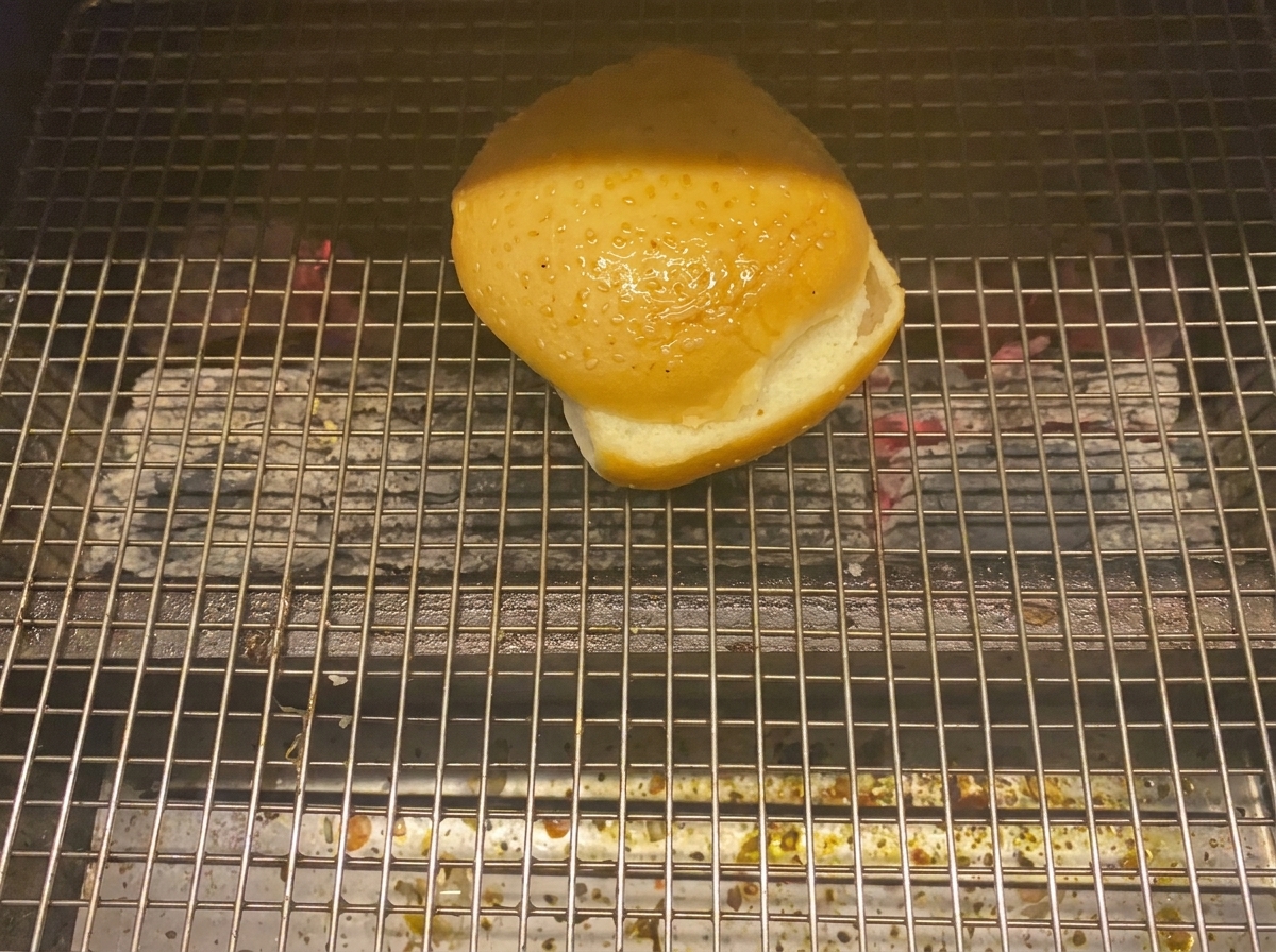 Połówka bułki do burgera opieka się na grillu węglowym.