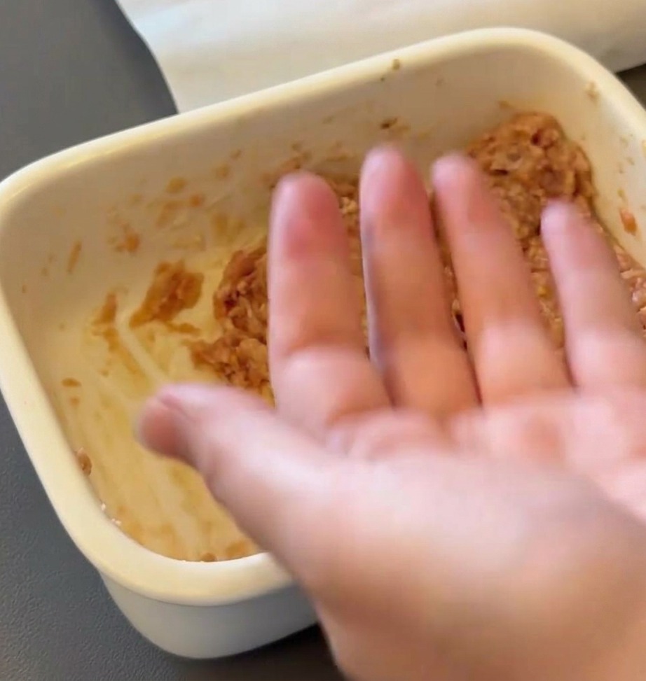 Dłoń formująca surową masę wołową w okrągły kotlet.