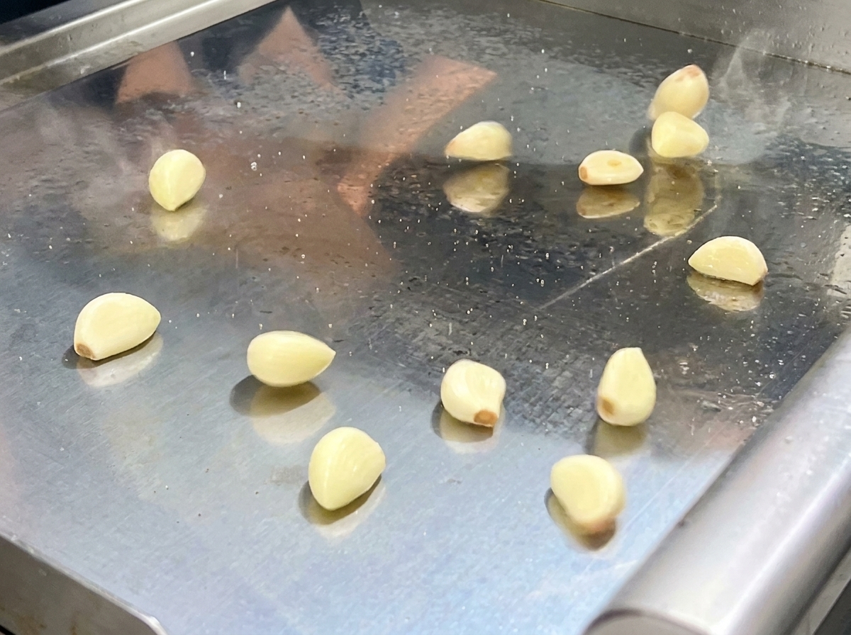 Podsmażona mieszanka papryk i aromatów przekładana do misy robota kuchennego.