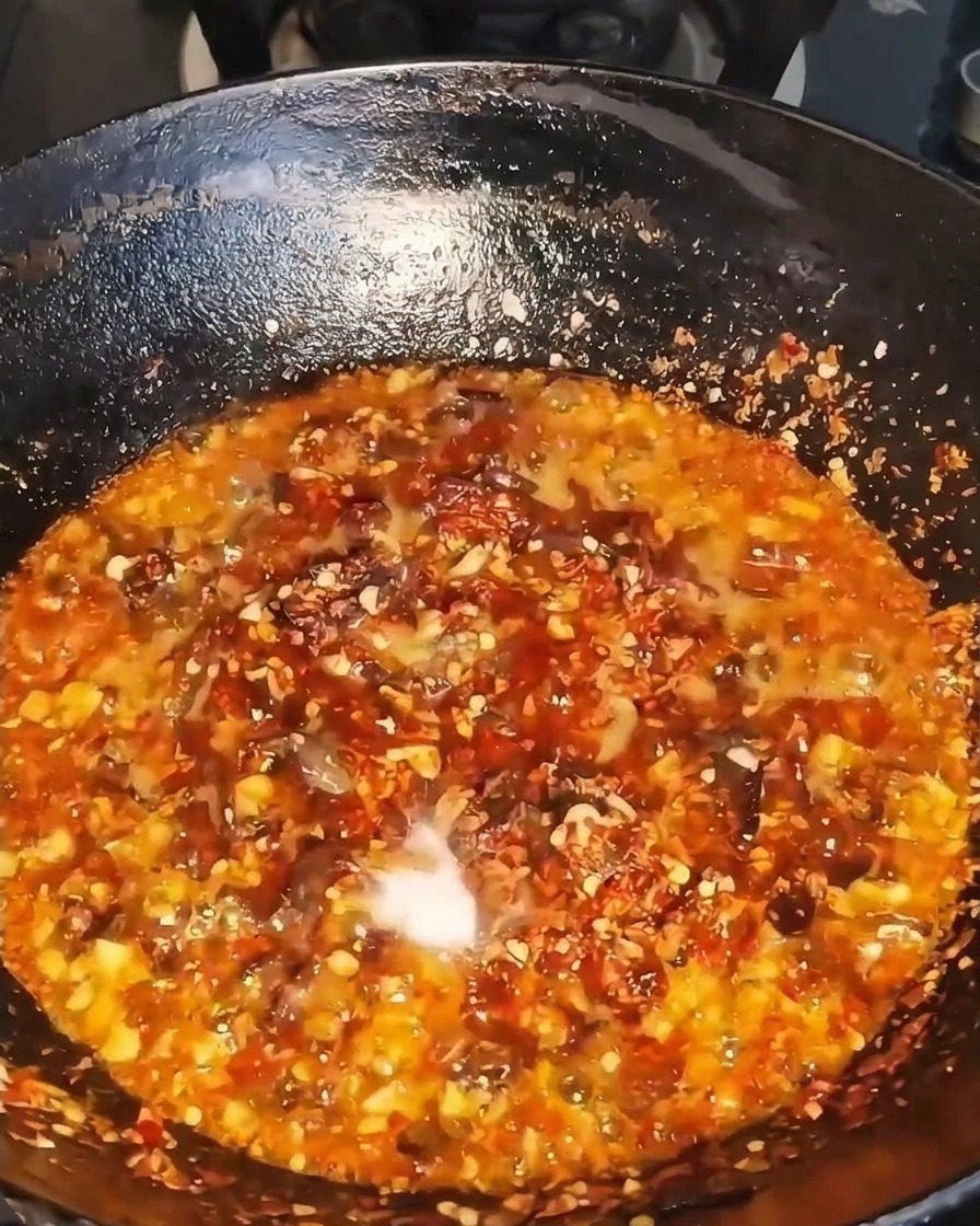 Ciemny płynny składnik wlewany do skwierczącego woka z wołowiną i chili.