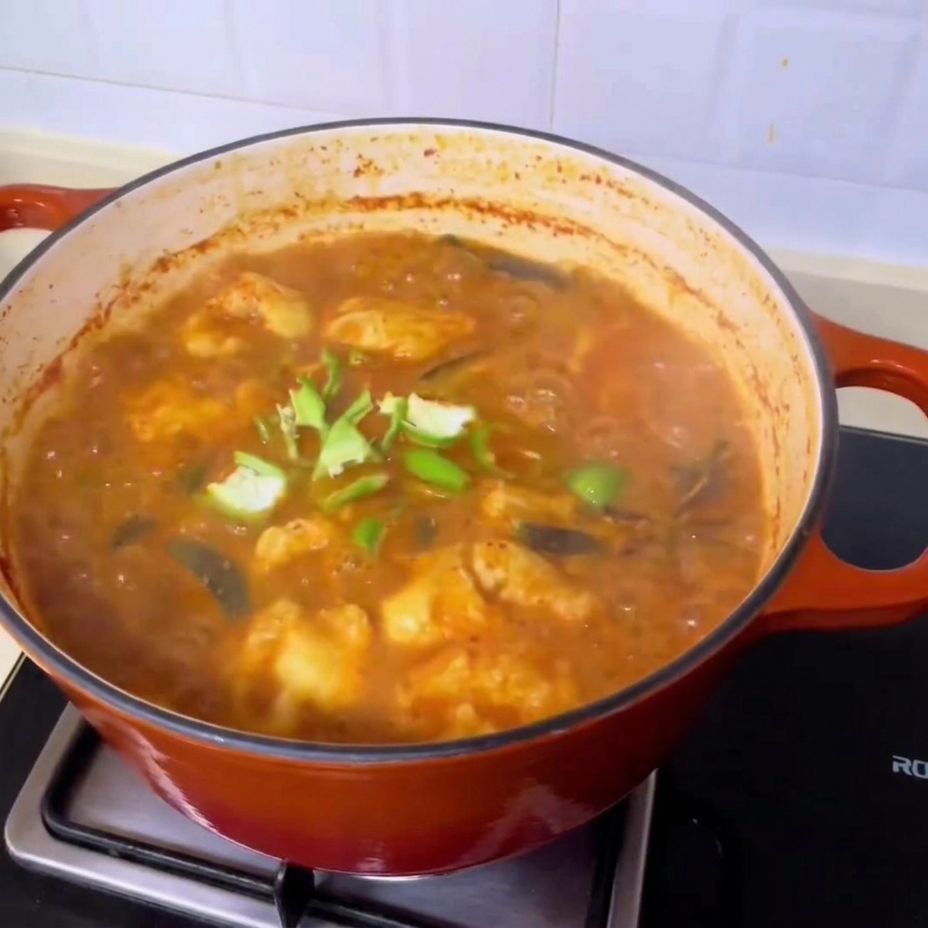 Świeże plastry zielonego chili posypane na wierzchu gotującej się, bogatej koreańskiej zupy z małżami.