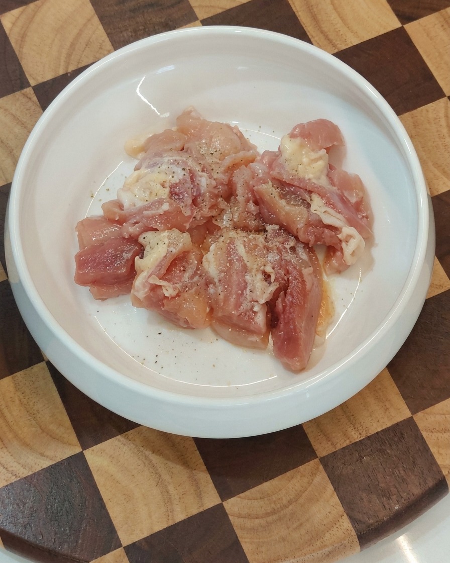 Miska z przyprawionymi surowymi kawałkami kurczaka.