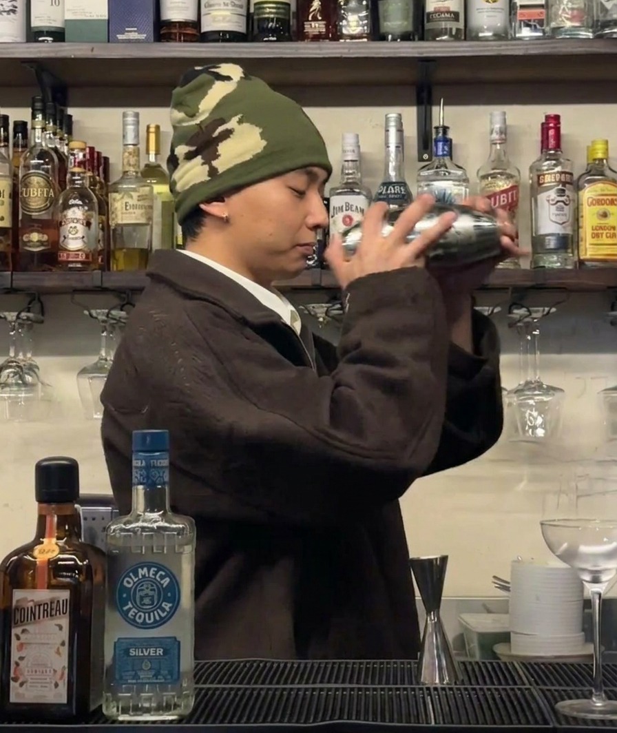 Barman energicznie potrząsający shakerem w celu schłodzenia składników.
