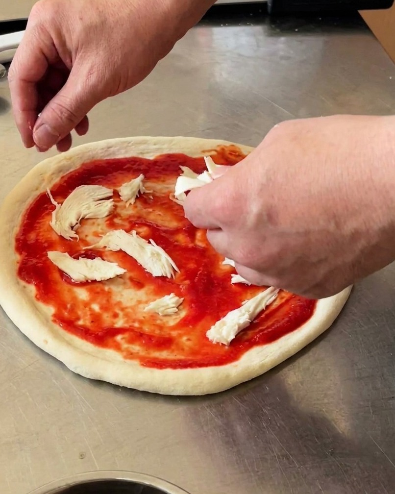 Pizza z kawałkami mozzarelli i zielonymi listkami bazylii.