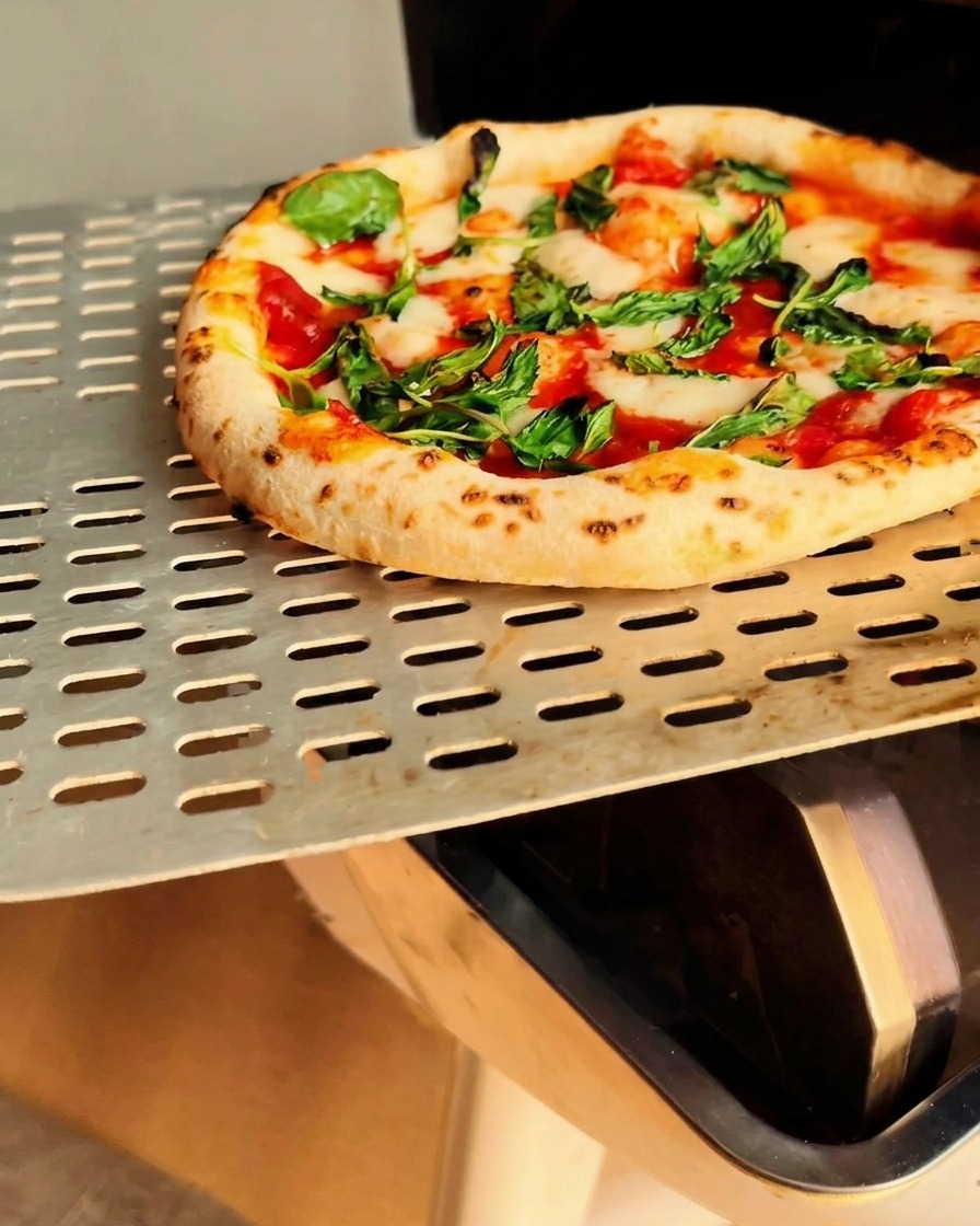 Gotowa, przypieczona pizza wyjmowana z pieca.