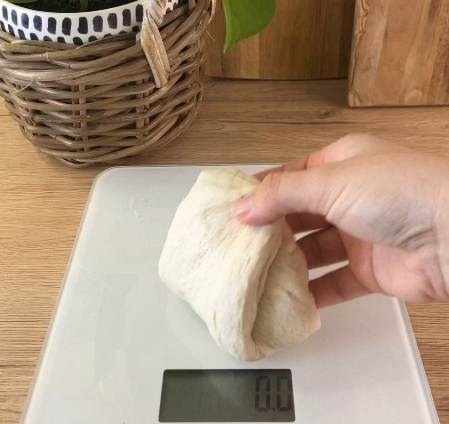 Porcja miękkiego, jasnego ciasta chlebowego spoczywająca na wadze kuchennej.