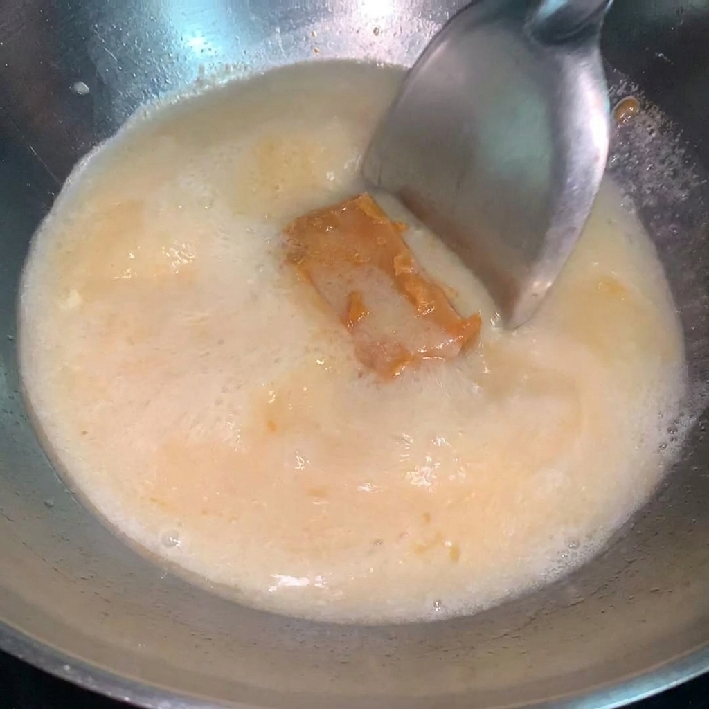 Łyżka skoncentrowanego sosu miso mieszana w gotującym się bulionie na ramen.