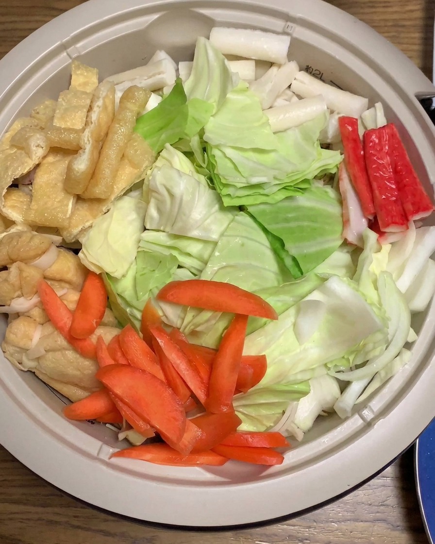 Pasta miso wylewana na warstwę kapusty, marchwi i pozostałych składników w dużym garnku.