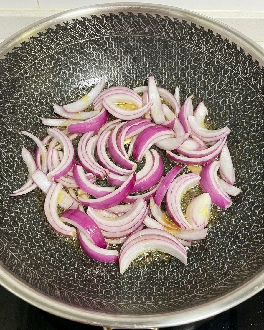 Piórka czerwonej cebuli smażone w rozgrzanym woku z olejem.