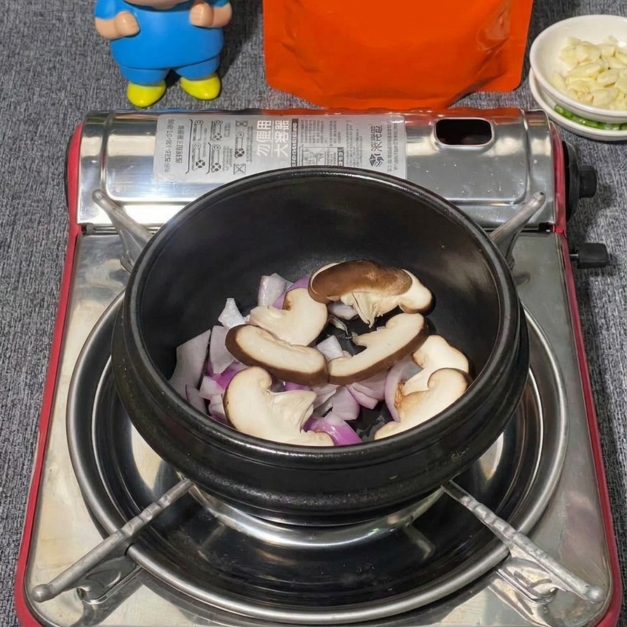 Różne grzyby, w tym pokrojone shiitake i kępki białych grzybów shimeji układane w czarnym kamiennym garnku na czerwonej cebuli.