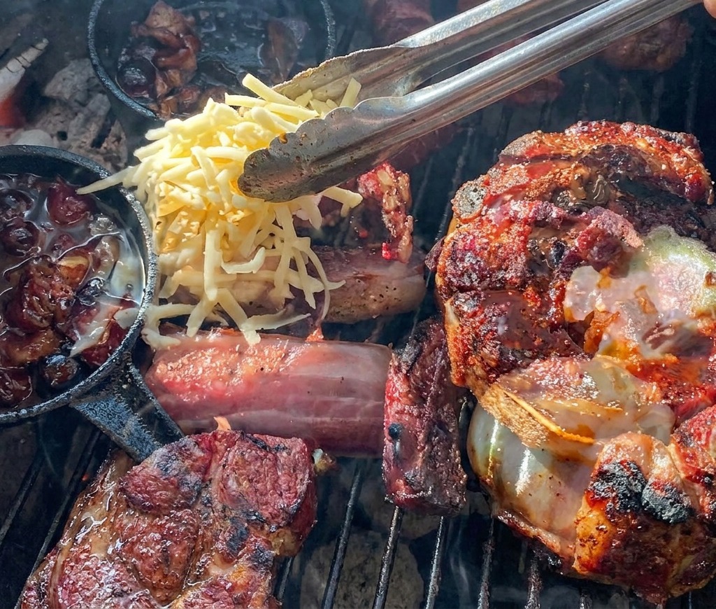Szczypce nakładające tarty żółty i biały ser na grillowany koszyczek z mięsa wypełniony ziemniakiem i sosem jagodowym.
