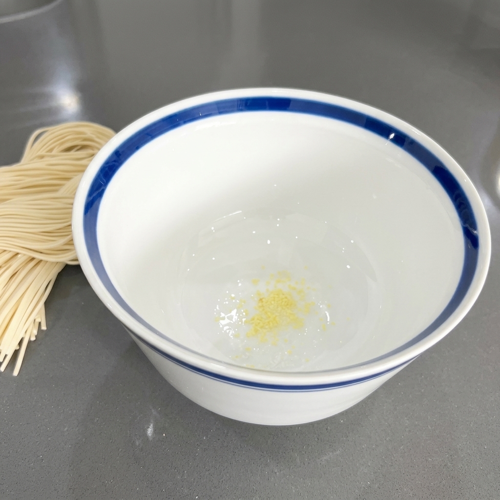 Małe kawałki posiekanego czosnku o żółtawym zabarwieniu na dnie białej ceramicznej miski.