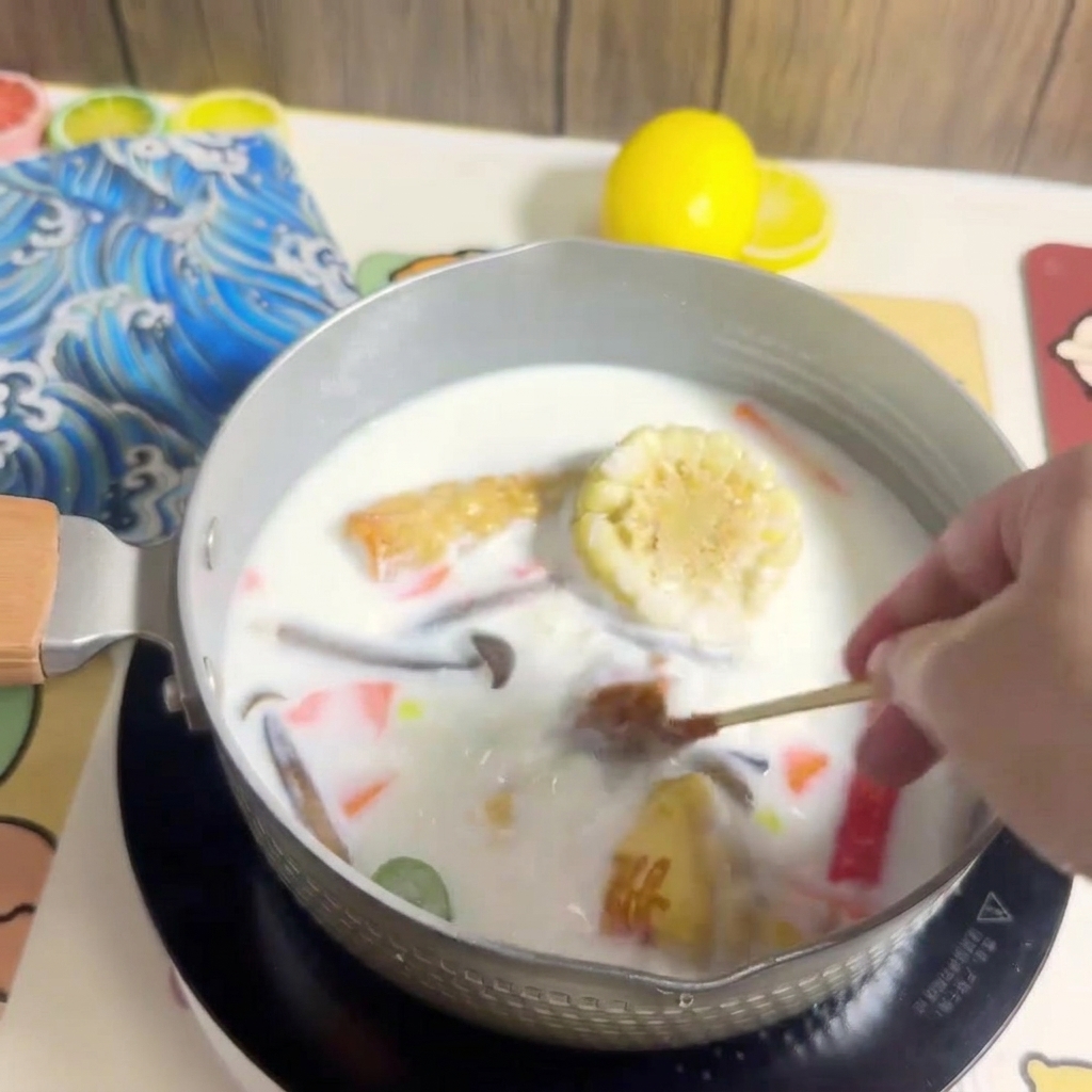 Porcja makaronu ramen wkładana do garnka z wrzącym wywarem i składnikami.