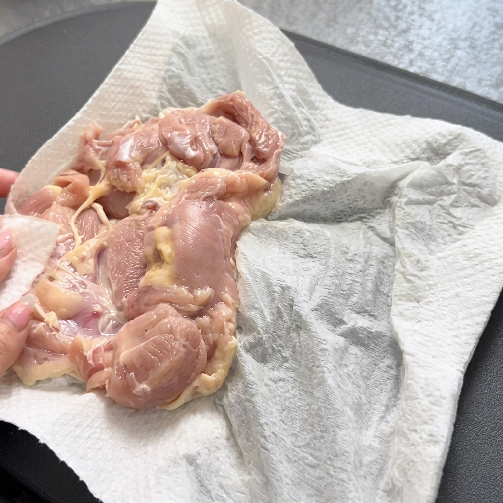 Używanie szczypiec do delikatnego umieszczenia kawałka kurczaka na gorącej patelni.
