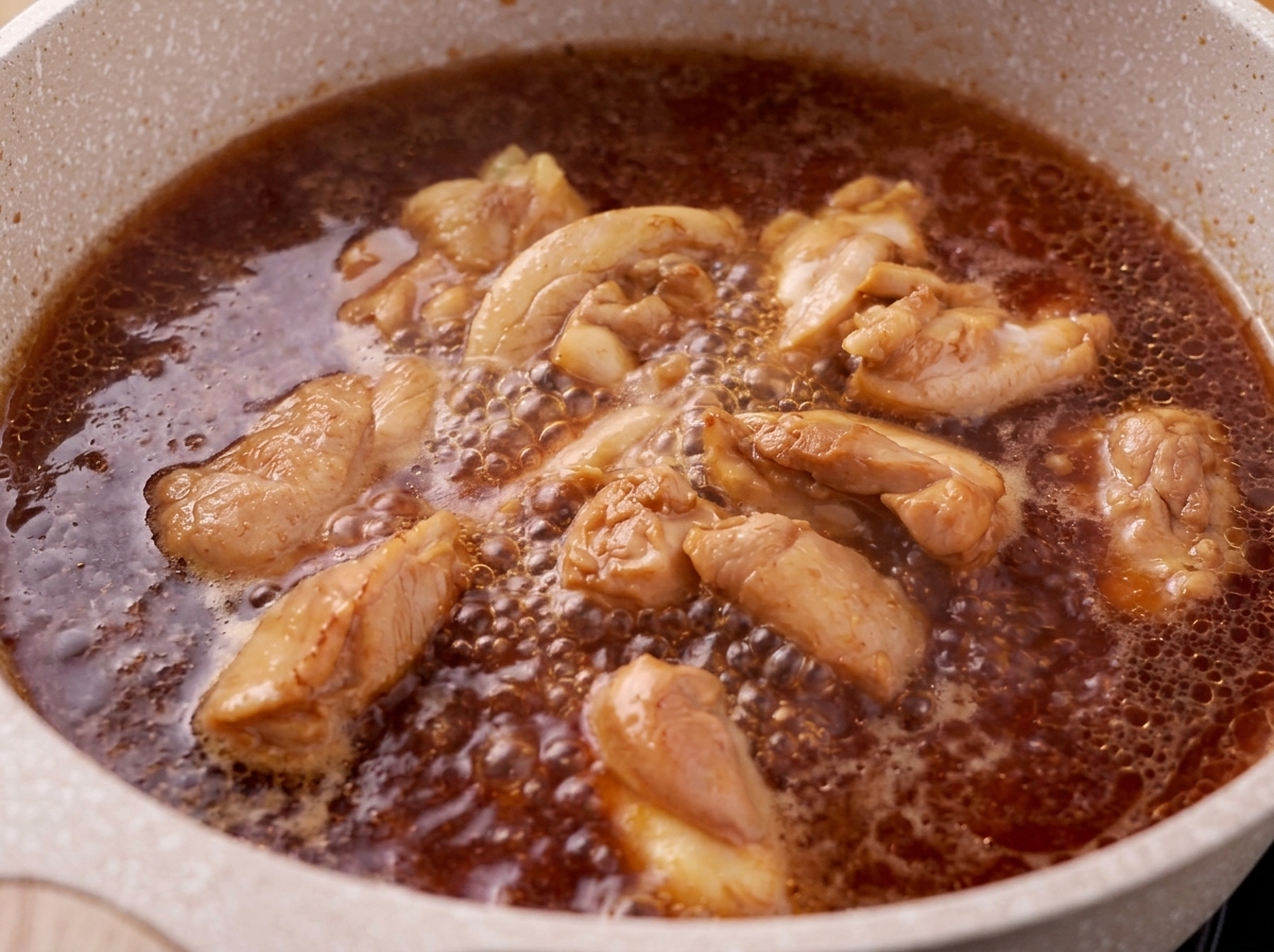 Piana zdejmowana z powierzchni gotującej się mieszanki kurczaka w sosie teriyaki.
