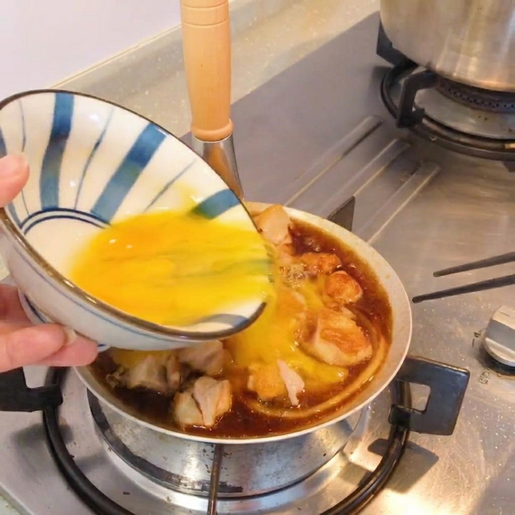 Gotowe danie Oyakodon na patelni, udekorowane zieloną cebulką.
