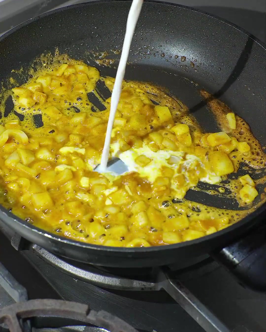 Mleczko kokosowe wlewane na patelnię z rozpuszczonym curry i podsmażoną cebulą, tworzące kremowy, żółty sos.