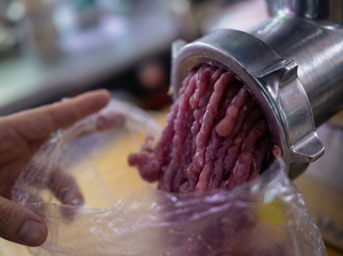 Zmielone mięso wydostające się z maszynki do mielenia mięsa do plastikowej torebki.