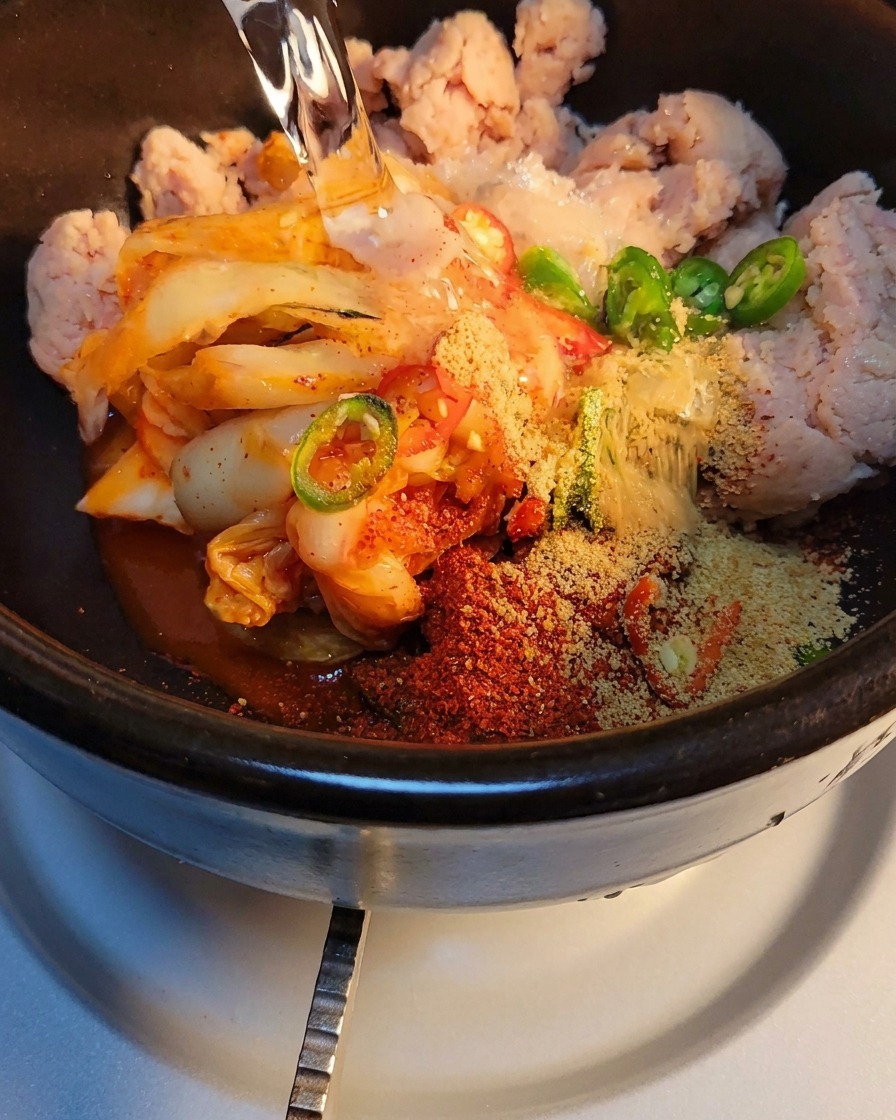 Woda wlewana do kamiennego garnka z kimchi i przyprawami.