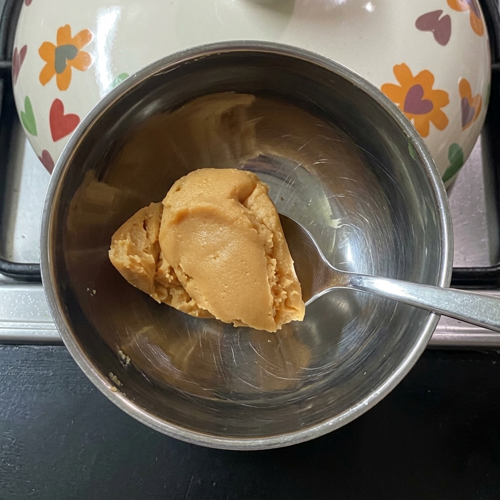 Mieszanie pasty miso z ciepłą wodą w małej miseczce.