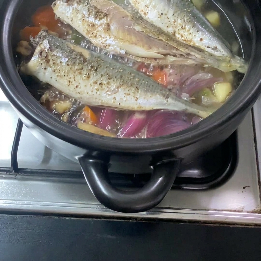 Wlewanie płynnej mieszanki miso do garnka z makrelą i warzywami.