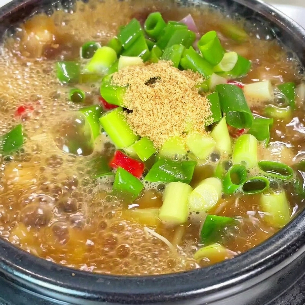 Zbliżenie na przyprawę wołową i czerwone płatki chili dodawane do garnka.