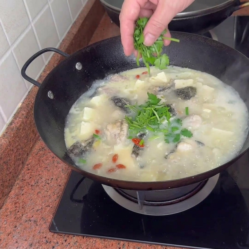 Gotowa zupa rybna z tofu i małżami udekorowana zieloną cebulką.