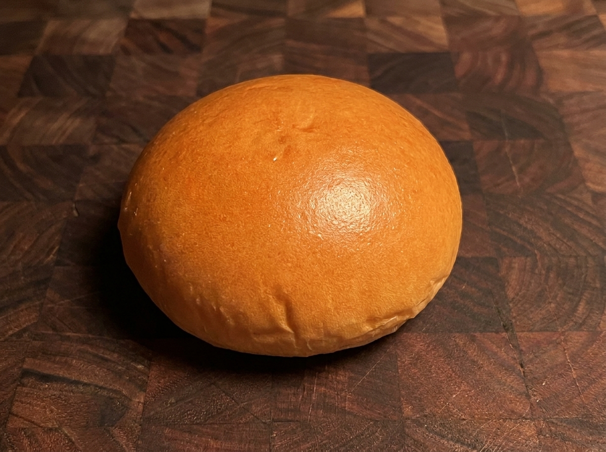 Złocista, opieczona bułka do burgera na drewnianej powierzchni.