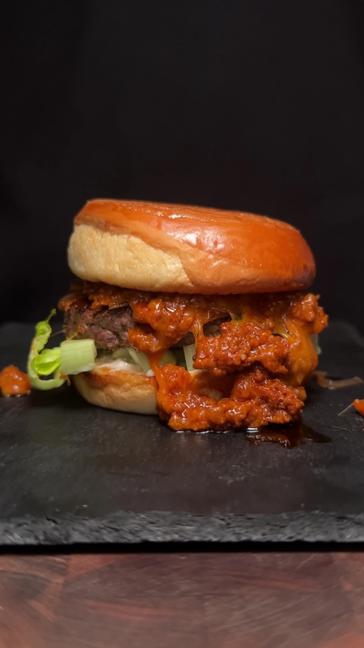 Gourmet burger Choriqueso z grubym kotletem wołowym i wyrazistym sosem serowym z chorizo na podpieczonej bułce.