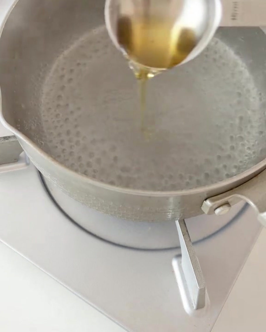 Suchy makaron fusilli wsypywany do garnka z wrzącą wodą.