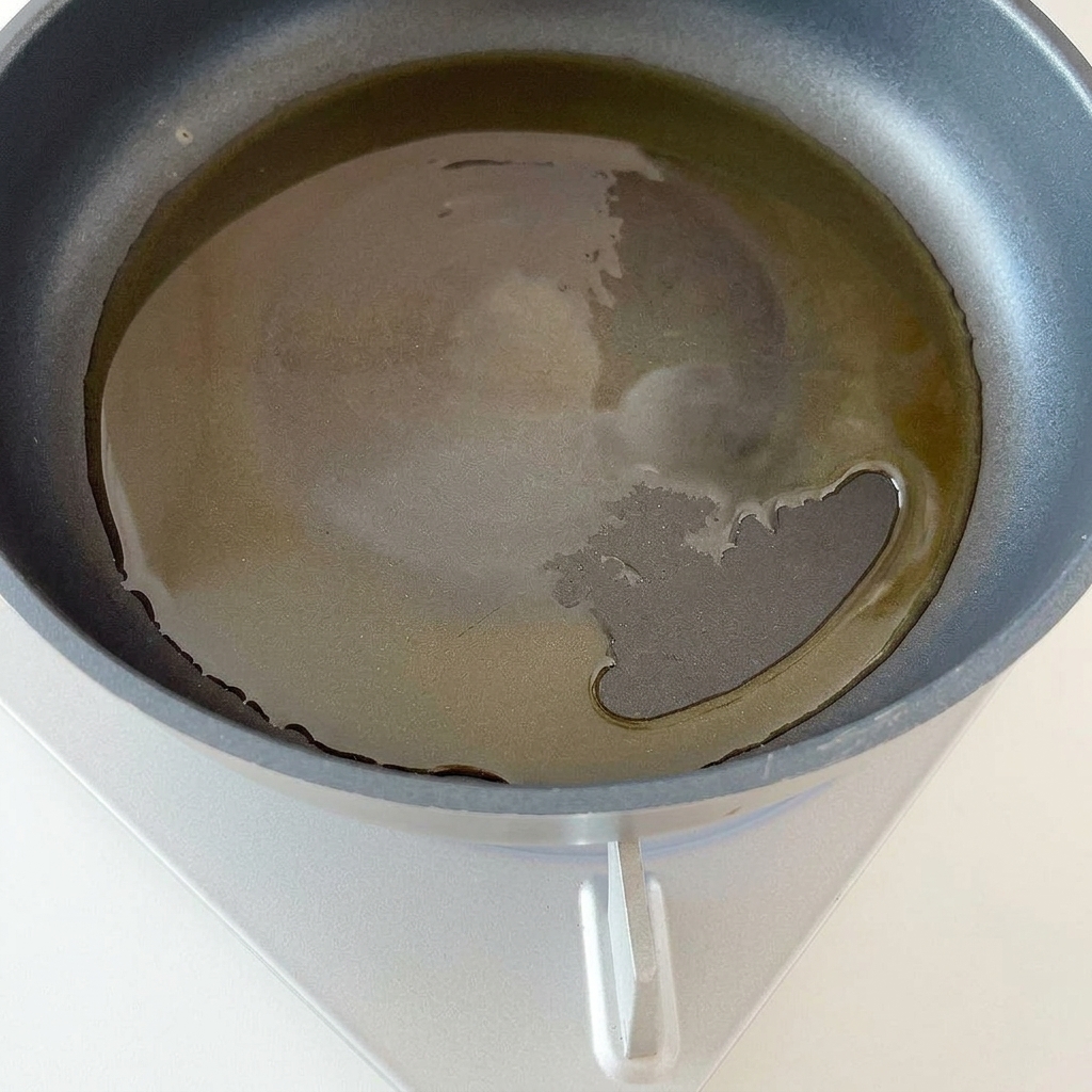 Posiekana czerwona cebula smażąca się na patelni z olejem.