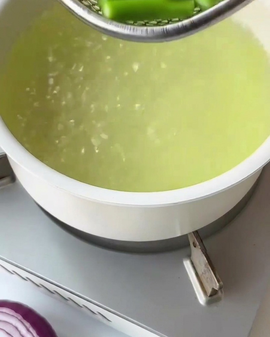 Suchy makaron fusilli wrzucany do garnka z wrzącą wodą.