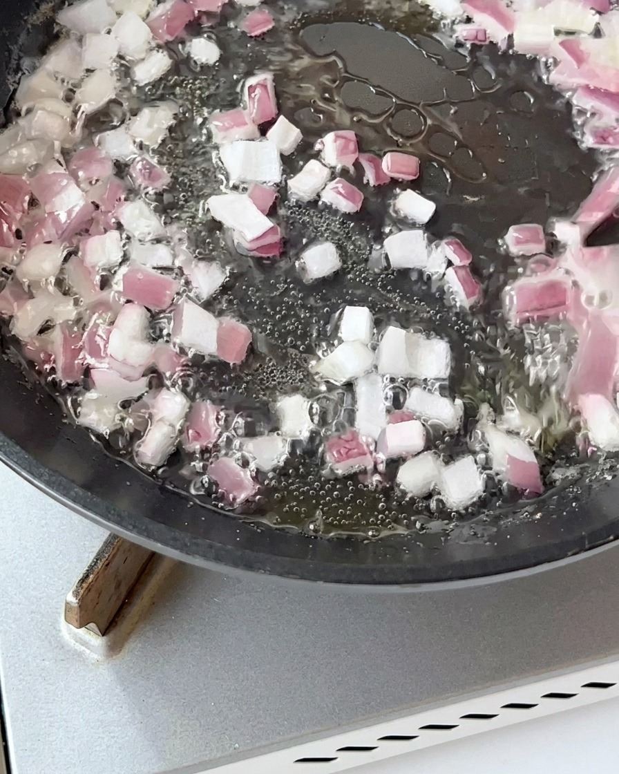 Kawałki boczku smażone na patelni z cebulą aż do uzyskania złotego koloru.