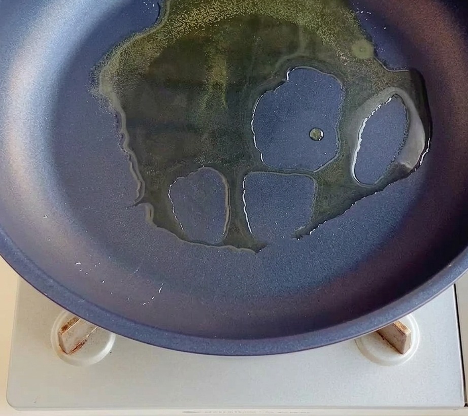 Posiekana czerwona cebula smażąca się na patelni z olejem.