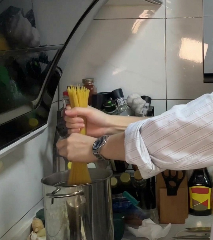 Spaghetti wkładane do garnka z wrzącą wodą, olejem i solą.