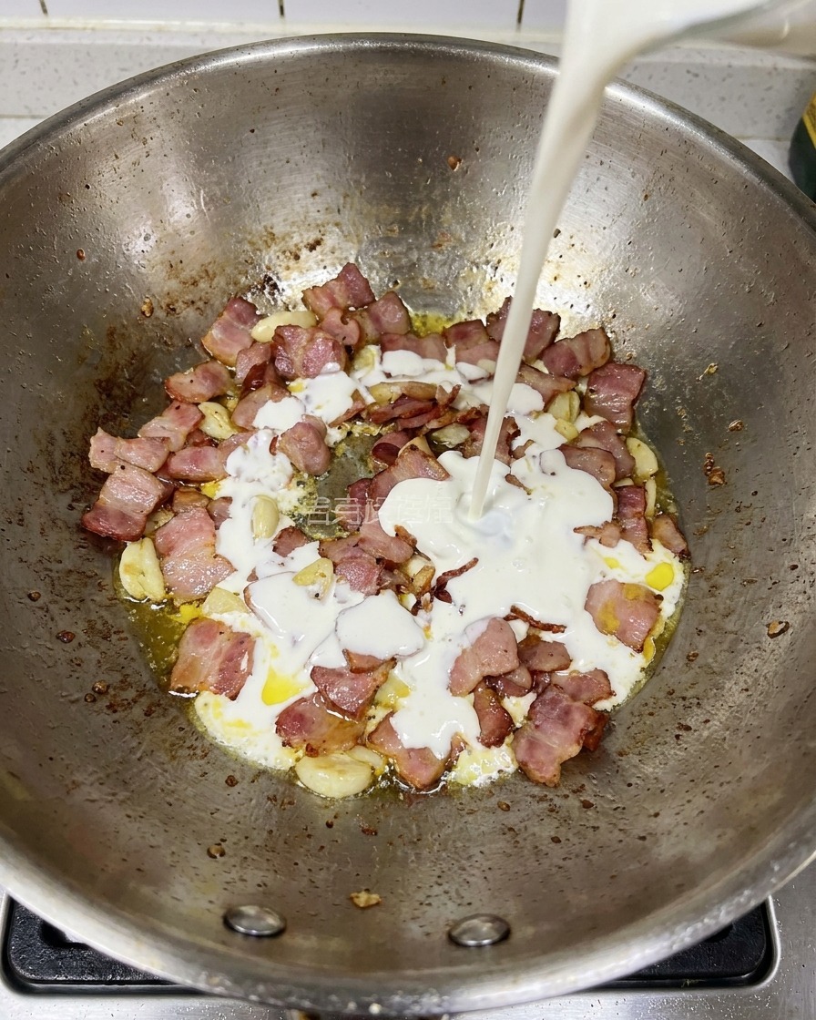 Śmietanka wlewana na patelnię z podsmażonym boczkiem i kawałkami czosnku.