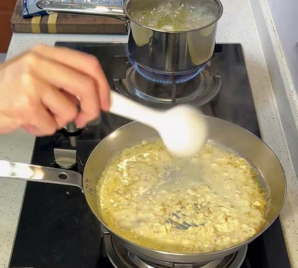 Szczypce przenoszące makaron al dente z garnka na patelnię z kremowym sosem.
