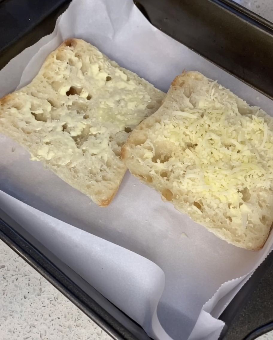 Tarty parmezan posypywany na posmarowane masłem kromki ciabatty.