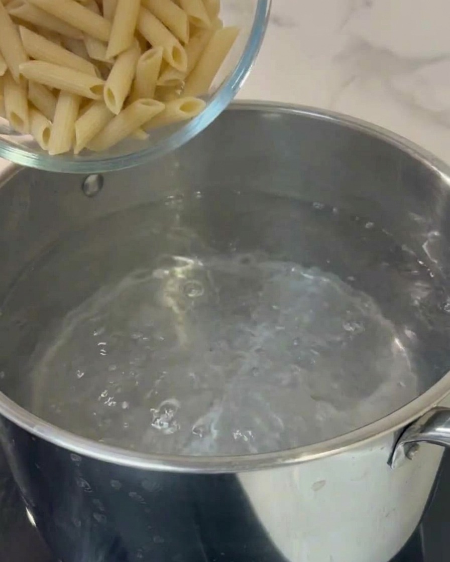 Makaron penne wrzucany do garnka z wrzącą wodą.