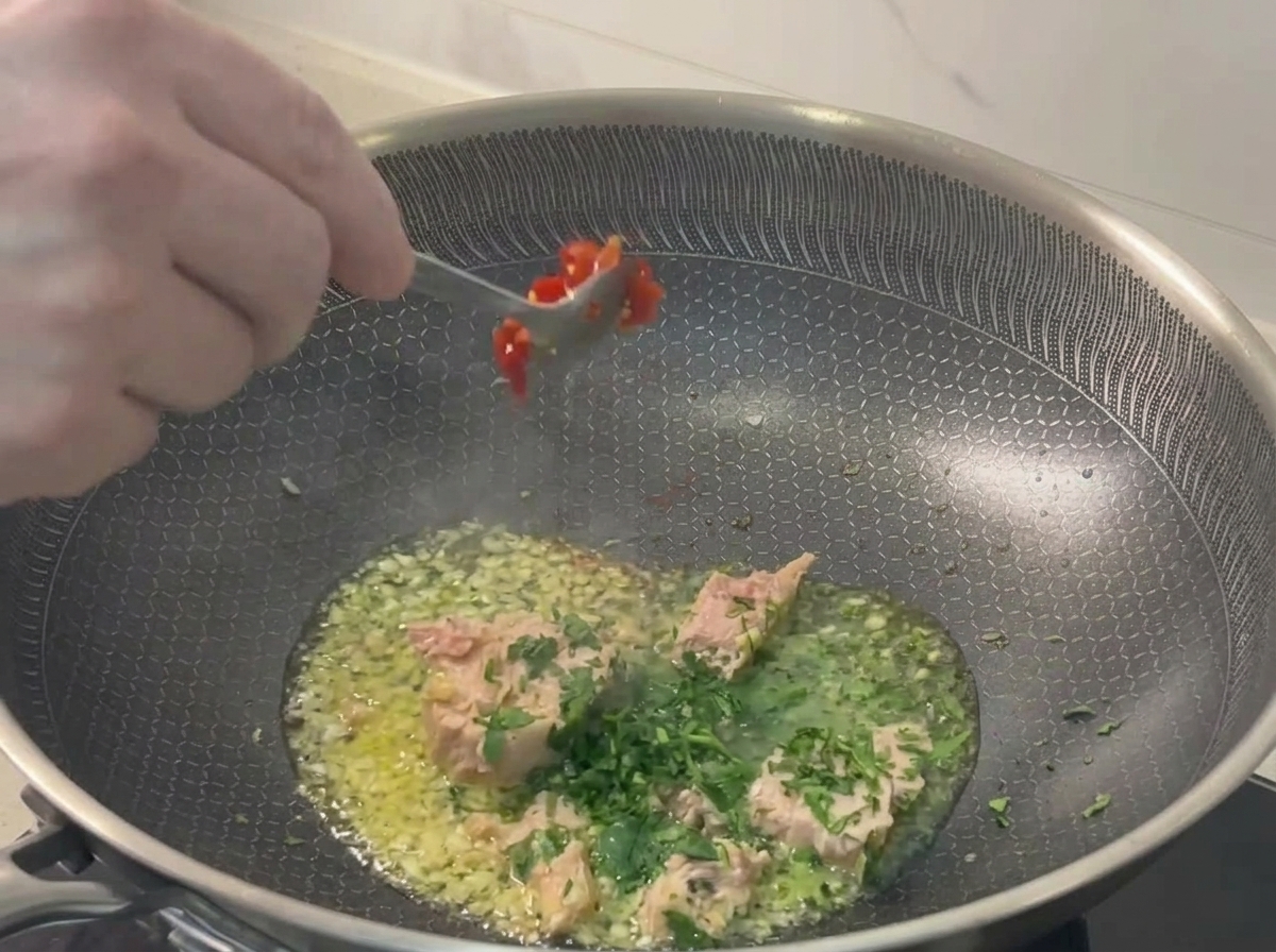 Dodawanie posiekanego czerwonego chili na patelnię.