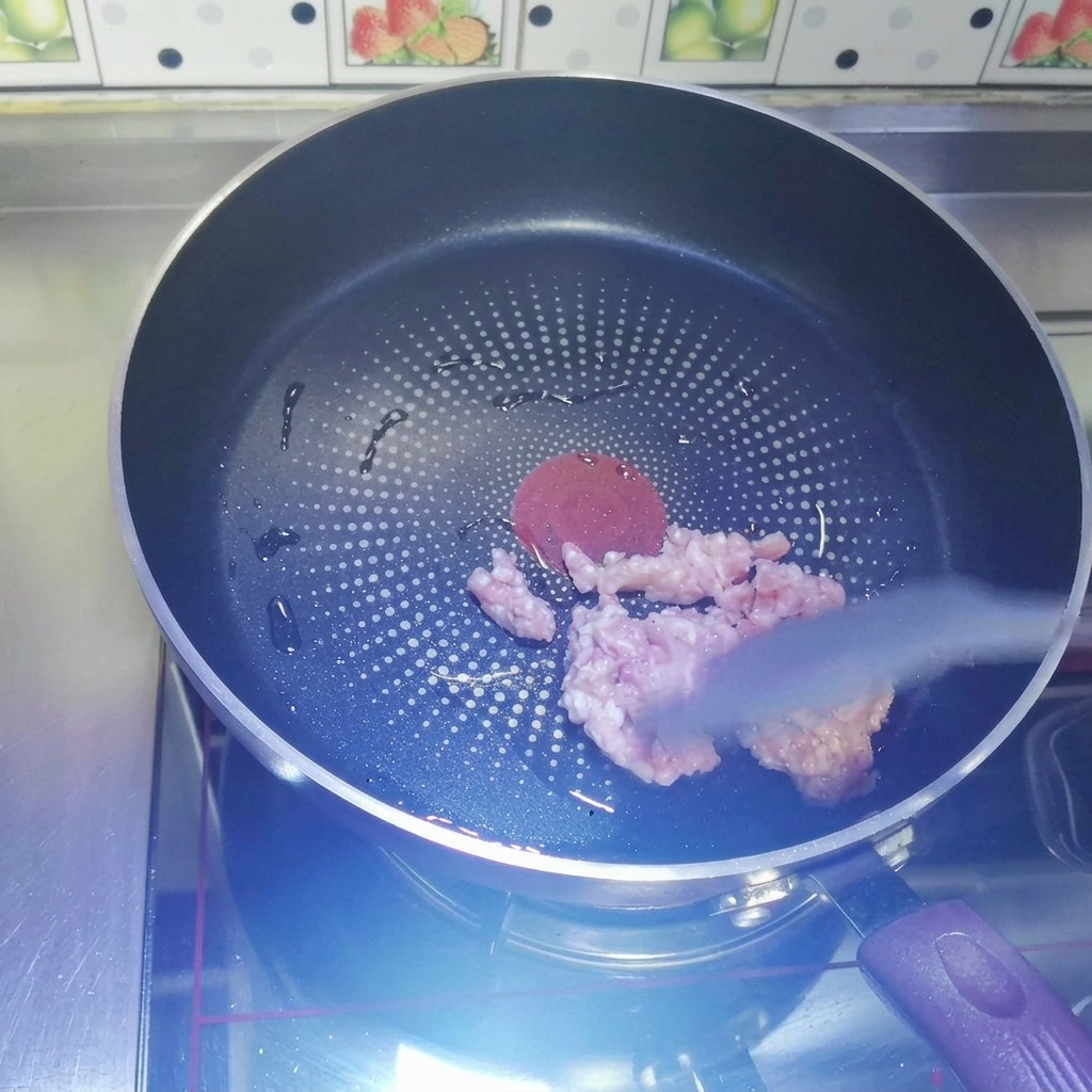 Surowe mięso mielone smażące się na ciemnej patelni.