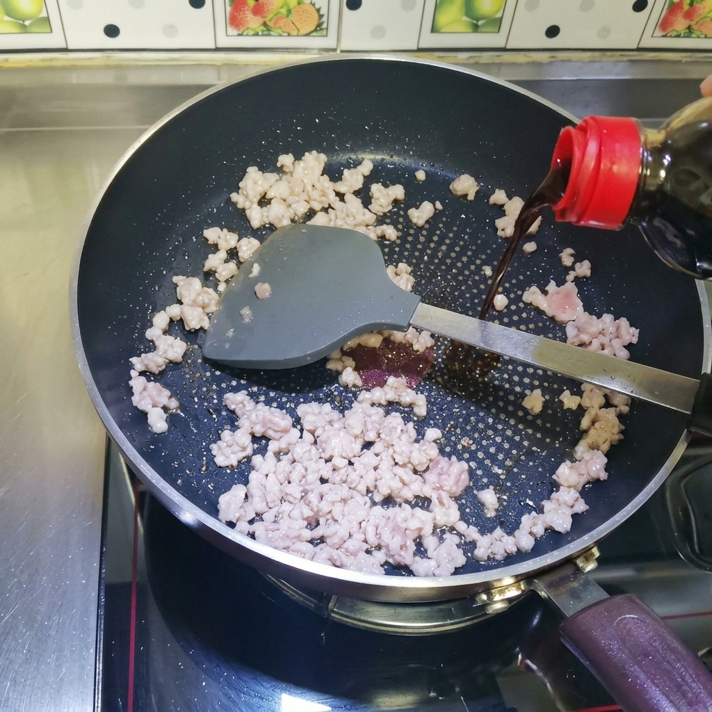 Sos sojowy wlewany na zrumienione mięso na patelni.