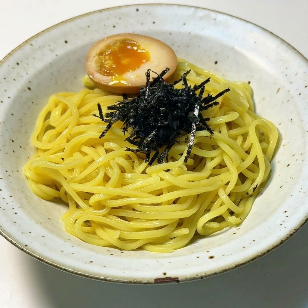 Wyłożony makaron ramen z posiekanymi czarnymi wodorostami i przekrojonym na pół jajkiem z płynnym żółtkiem.