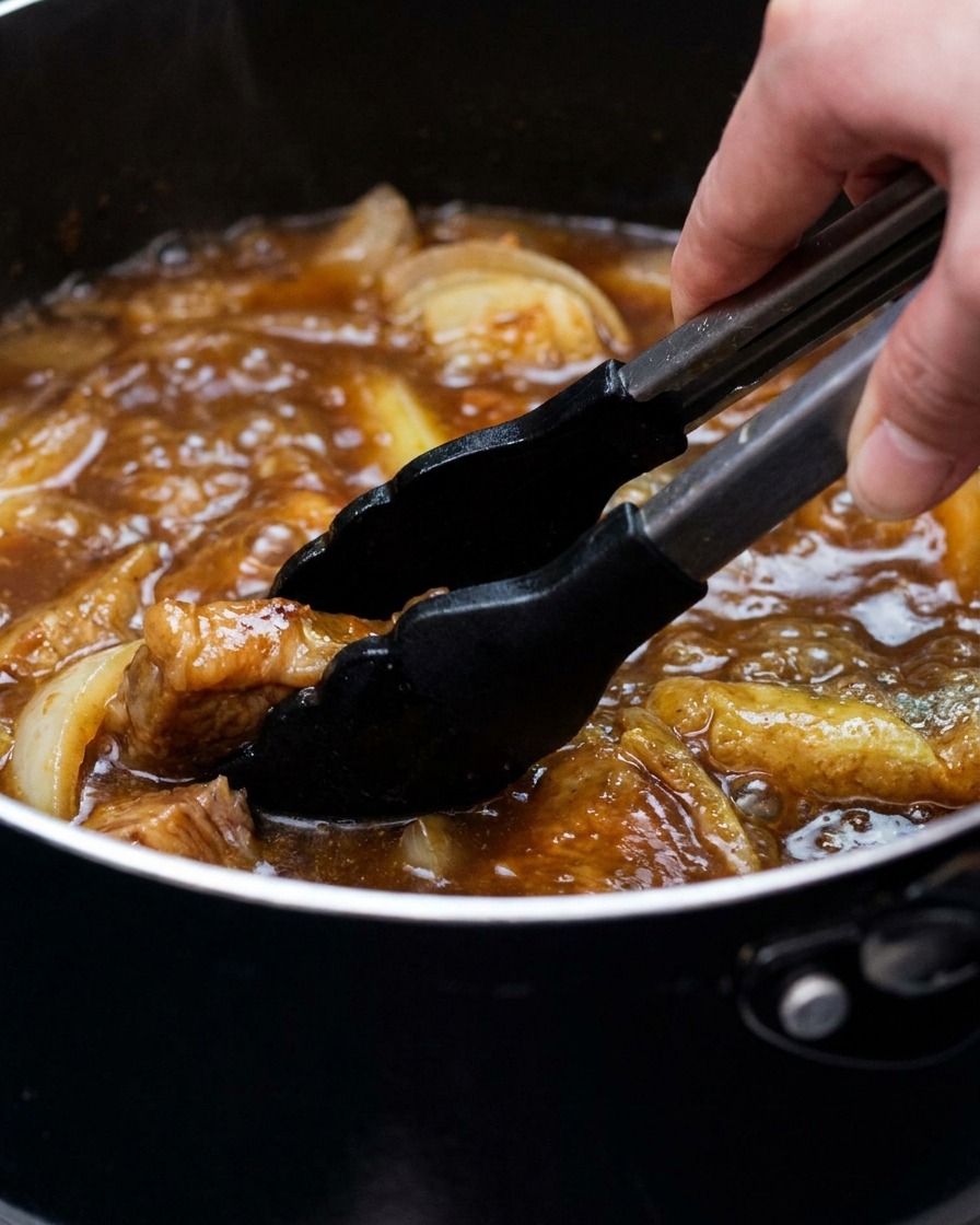 Garnek z bulionem curry, tofu i cebulą, powoli mieszany szczypcami.
