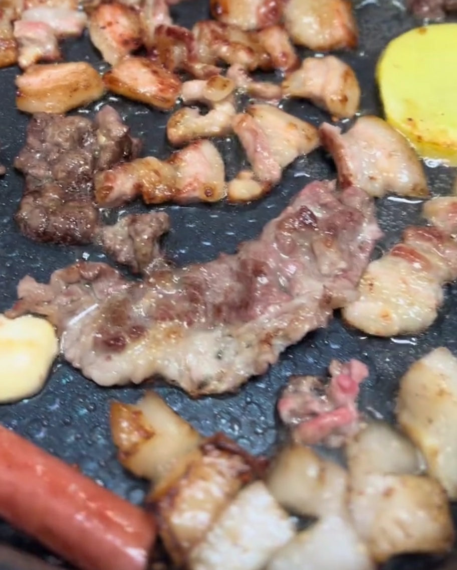 Boczek, pieczarki i plastry ziemniaków skwierczące na grillu elektrycznym z ładnym złocisto-brązowym przypieczeniem.