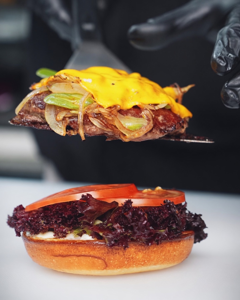 Plastry cebuli i zielonej papryczki chili podsmażane na gorącej, metalowej powierzchni grilla.