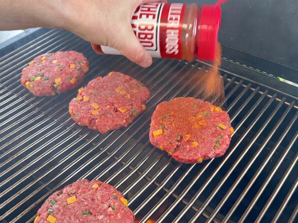 Kotlety wołowe przyprawione BBQ rub spoczywające na ruszcie grilla.