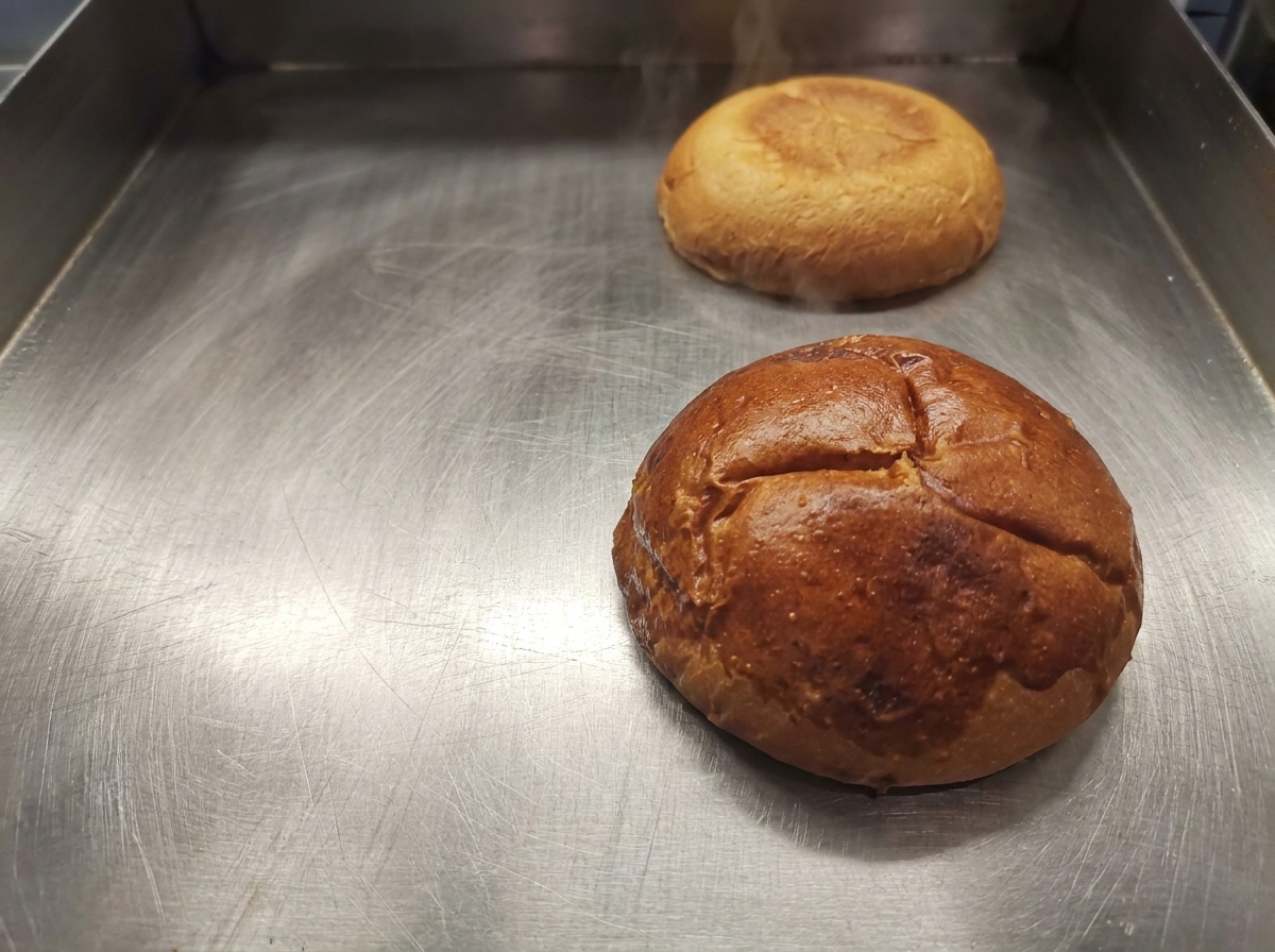 Połówki bułki do burgera o złotym kolorze leżące na czystej patelni.
