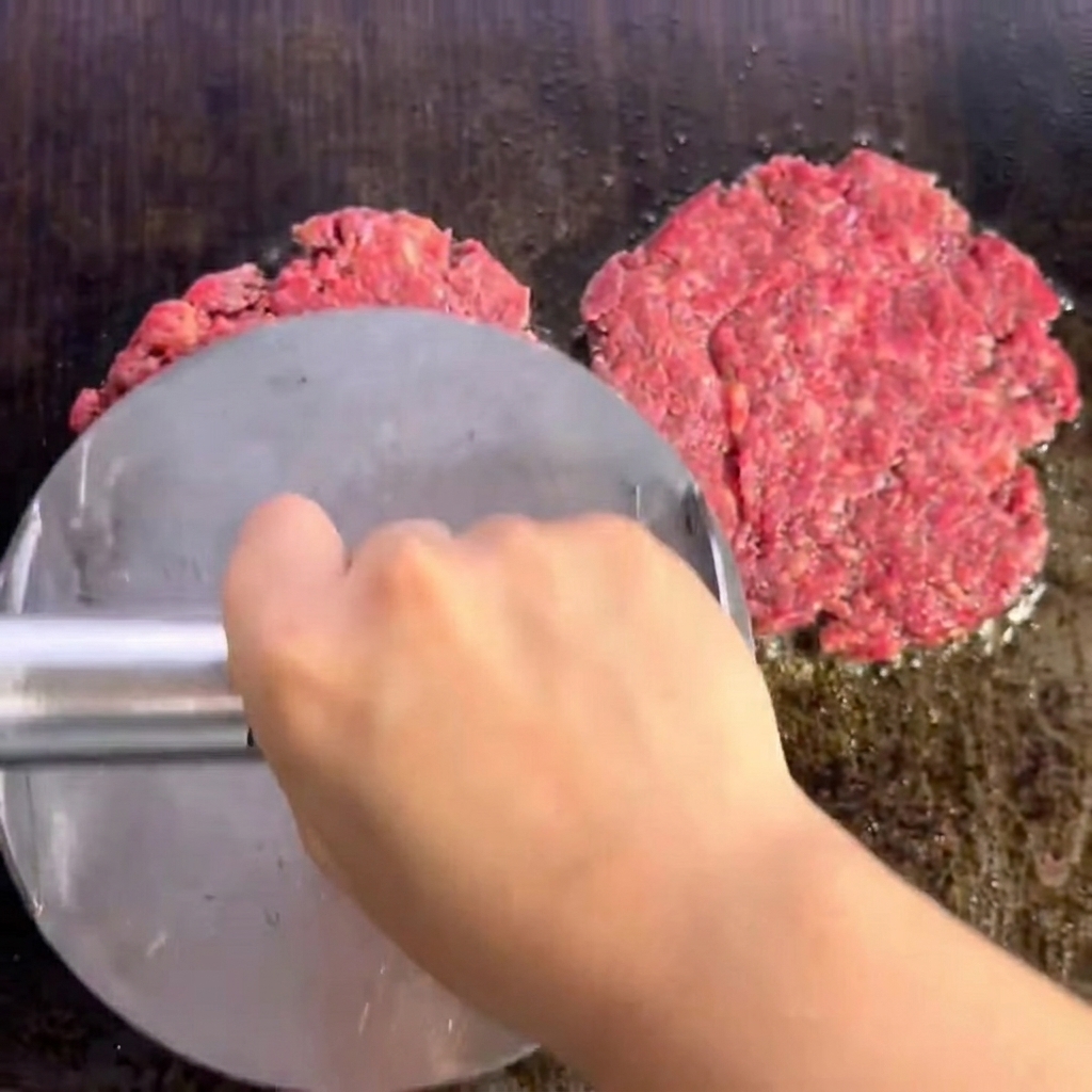 Dwa przyprawione kotlety wołowe na grillu z wyraźną skorupką.