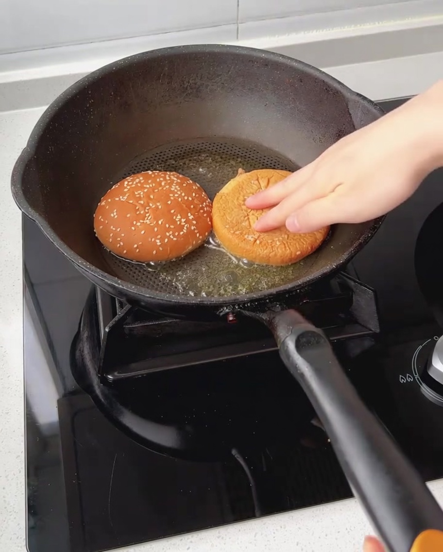Połówki bułki hamburgerowej opiekane w patelni z roztopionym masłem.